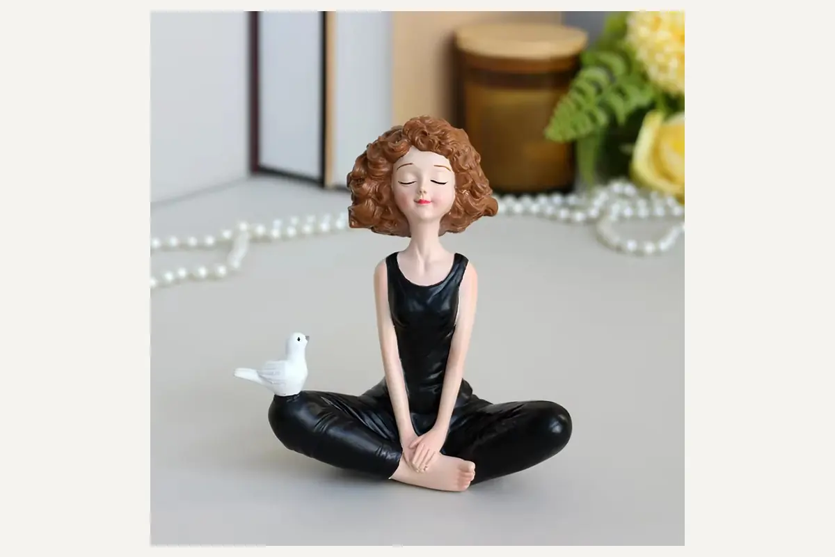 A seated woman figurine in a black outfit with a white bird