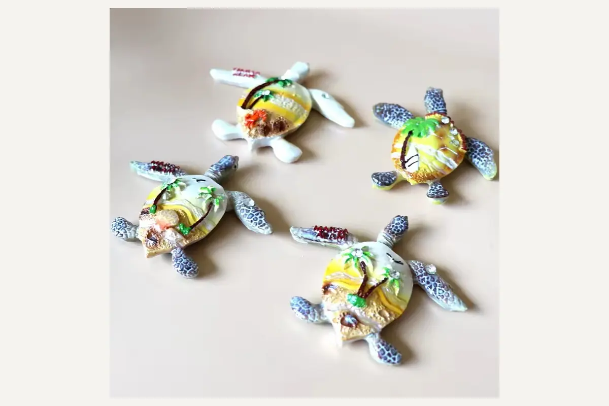 Four painted sea turtle magnets arranged on a pale surface