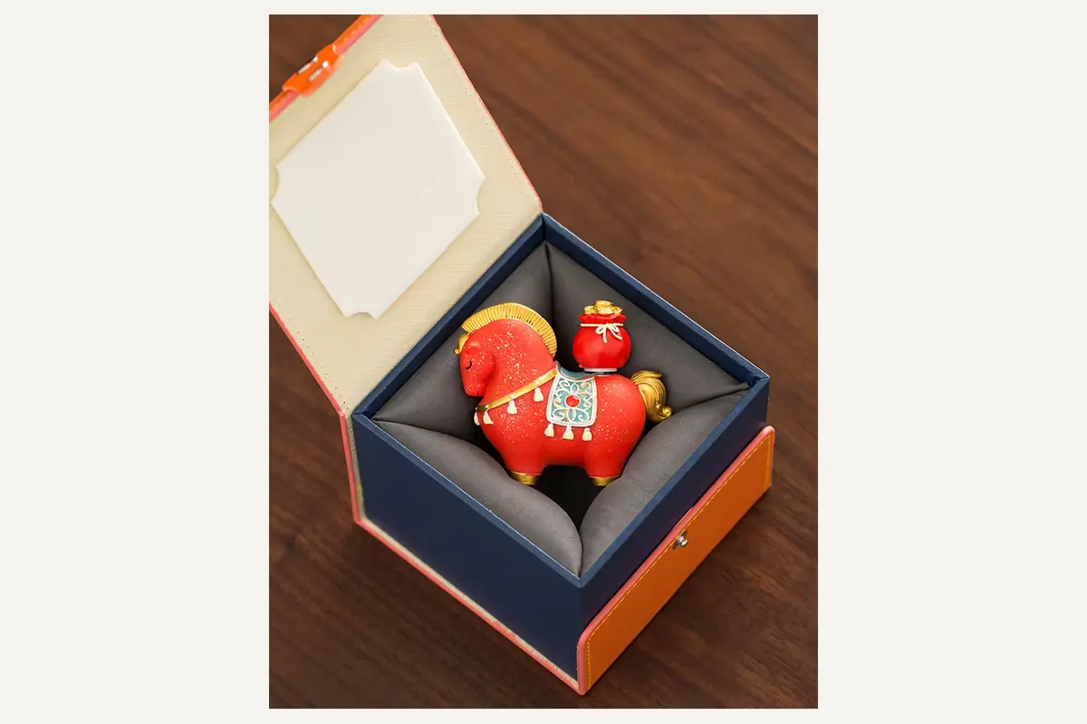 A red horse figurine in an open cushioned presentation box