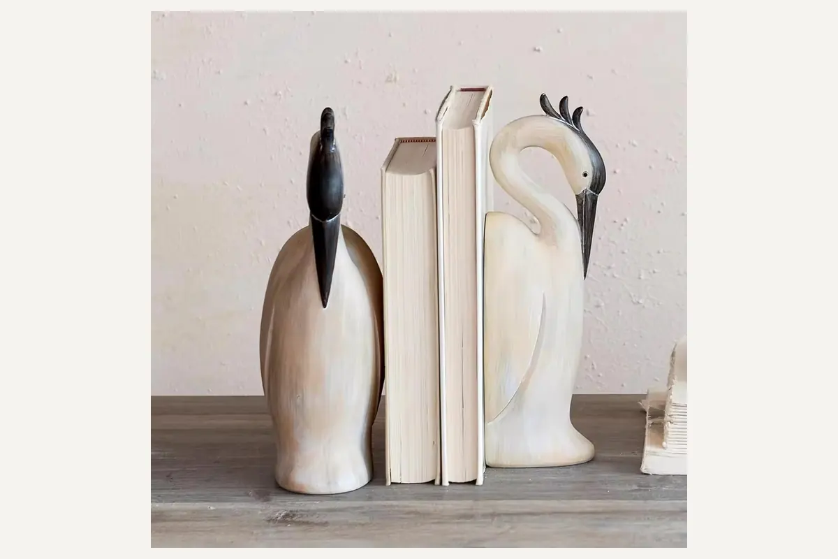 White and brown bird bookends holding books on a shelf