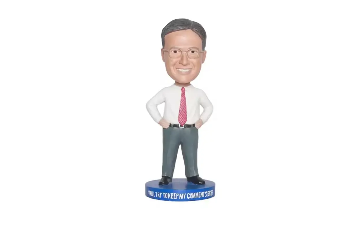 A shirt-and-tie character bobblehead on a blue base with a text band