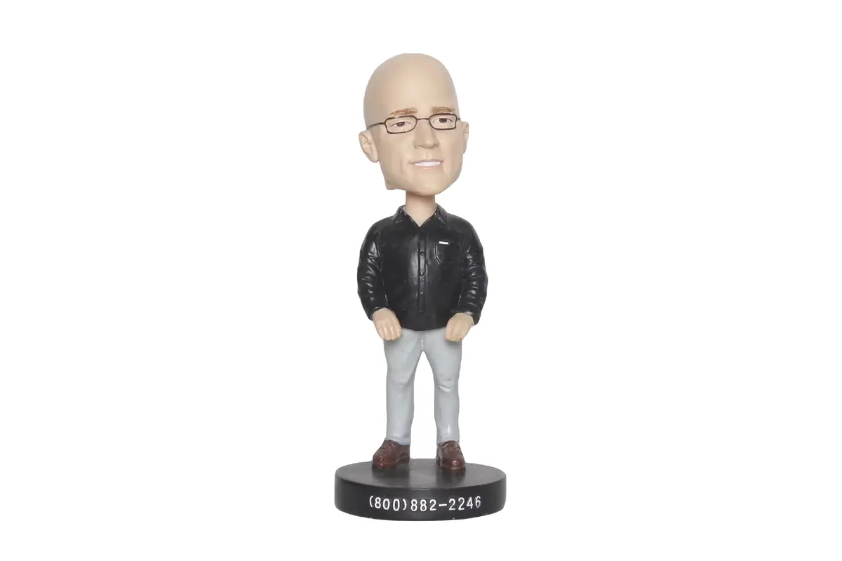 A bald character bobblehead wearing glasses and a black jacket