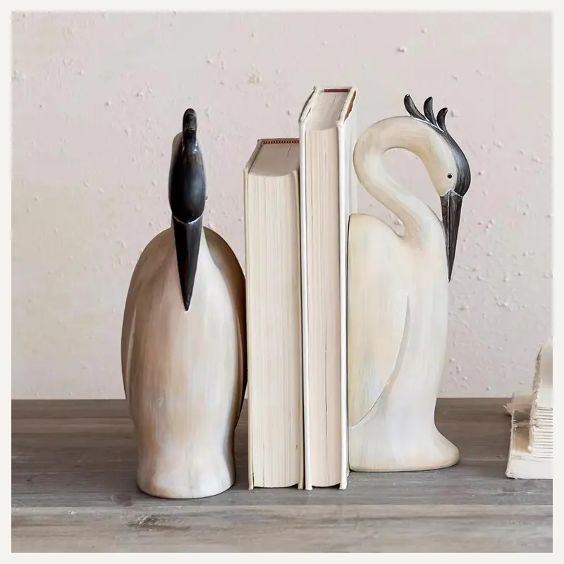 Cream heron-shaped bookends framing a small row of books