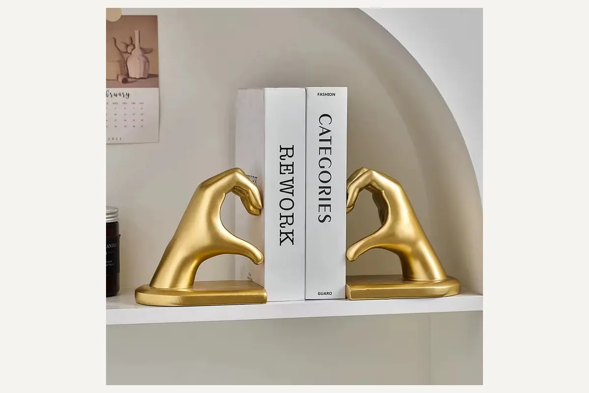 Gold-colored hand-shaped bookends making a heart around books