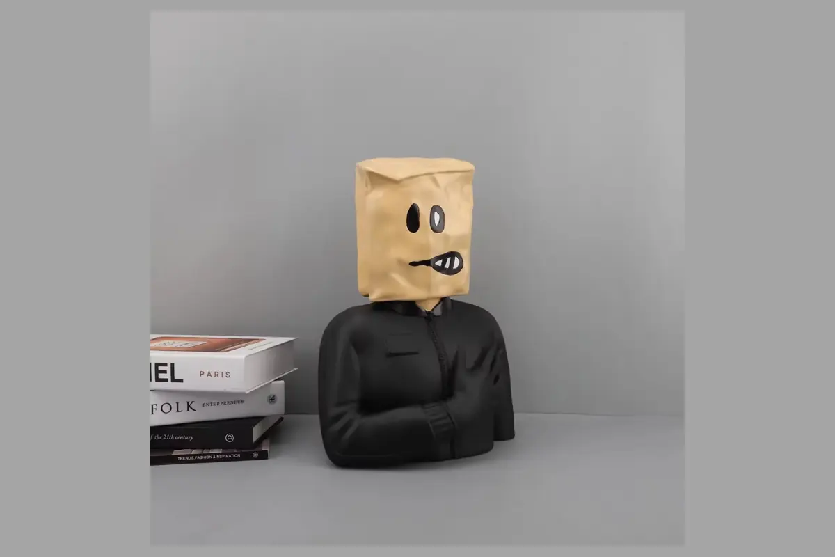 A black-clothed figure bust with a tan paper-bag-shaped head