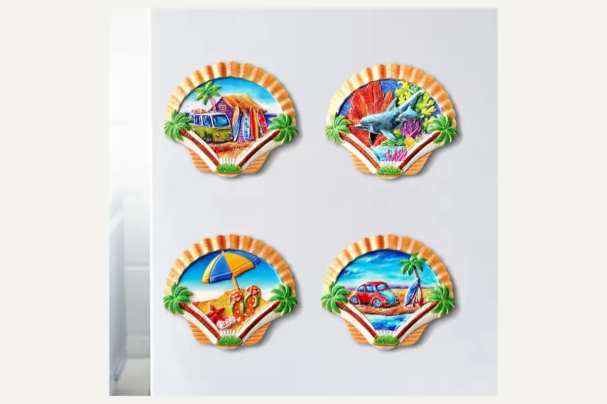 Four seashell-shaped magnets with colorful beach scenes
