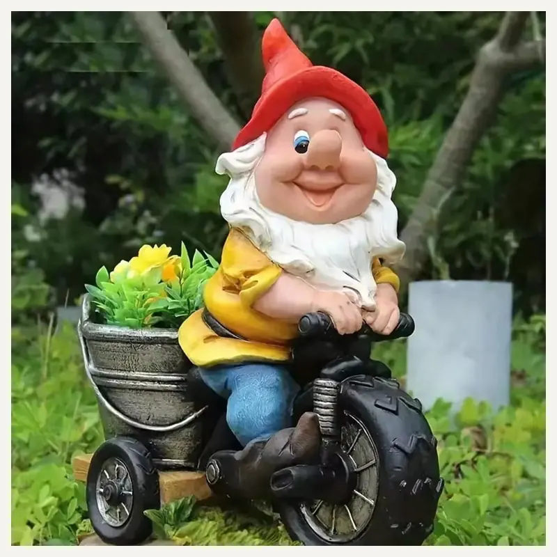 A red-hat garden gnome riding a black wheeled vehicle beside a flower bucket