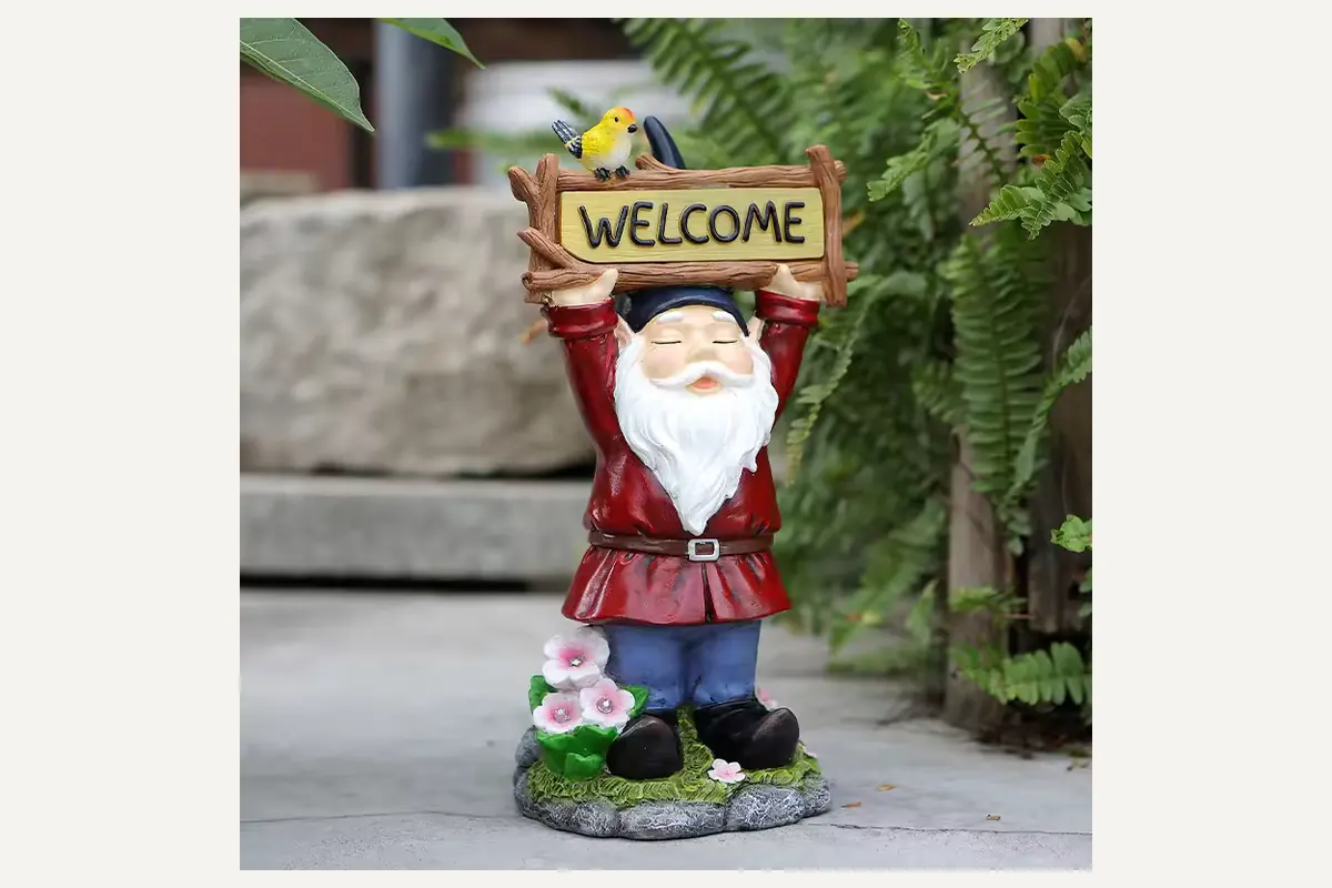 A garden gnome holding a welcome sign on an integrated stone-like base