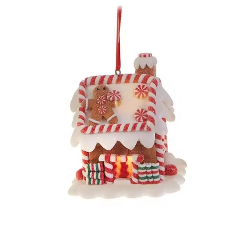 A gingerbread house hanging ornament with a red ribbon