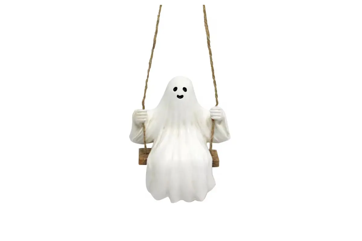 A white ghost hanging ornament seated on a small suspended swing