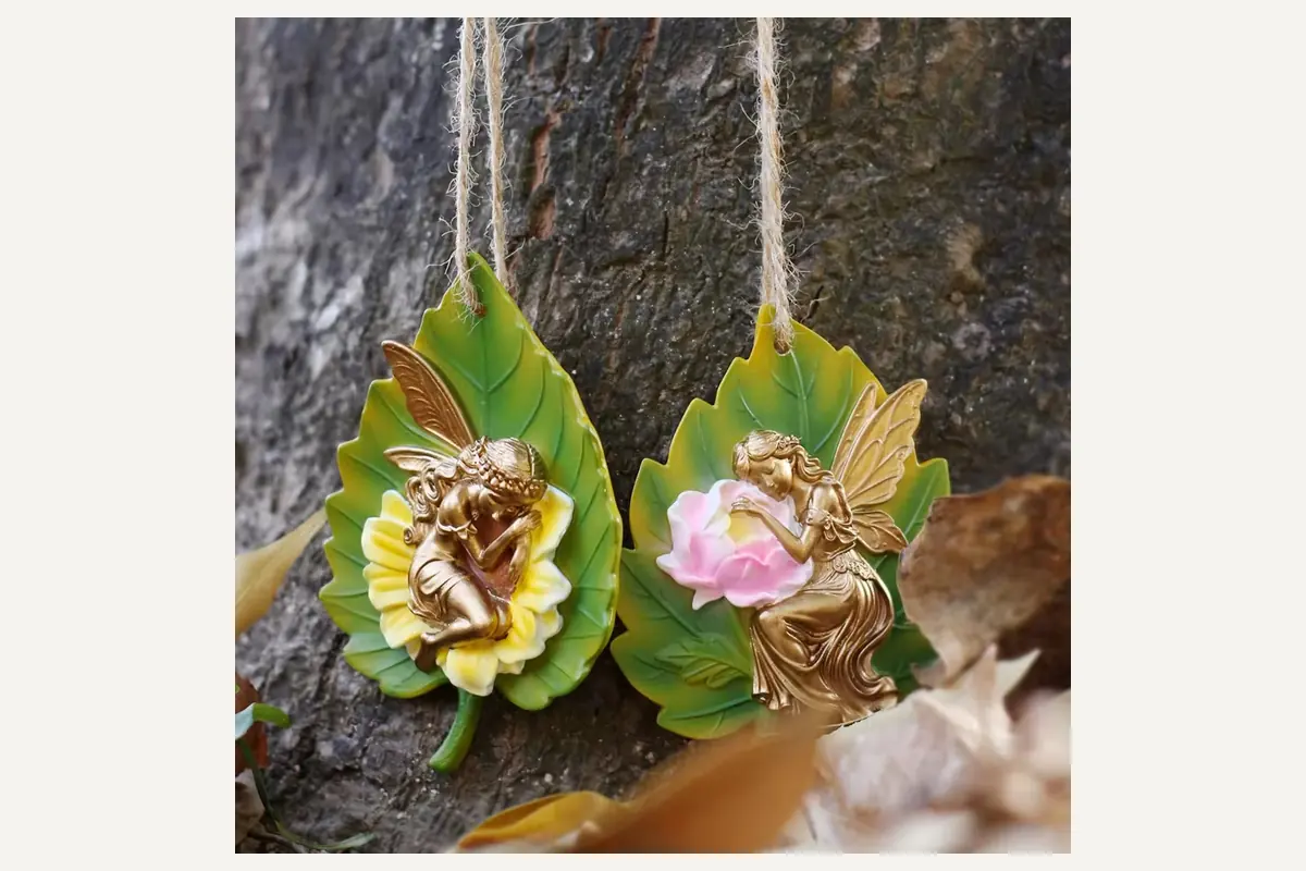 Two leaf-shaped hanging ornaments with small fairy figures