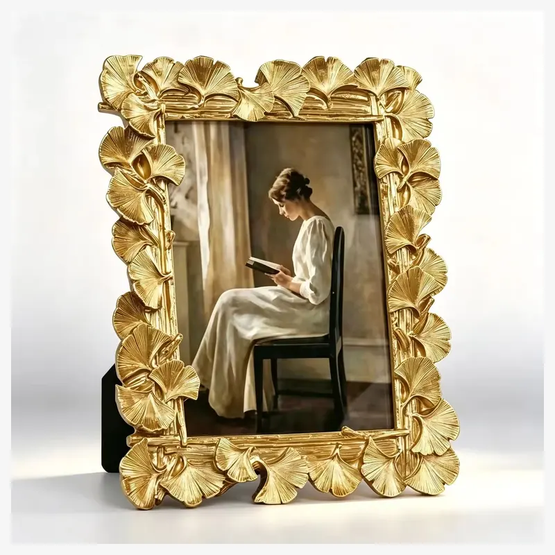 A gold-colored rectangular photo frame surrounded by ginkgo leaves