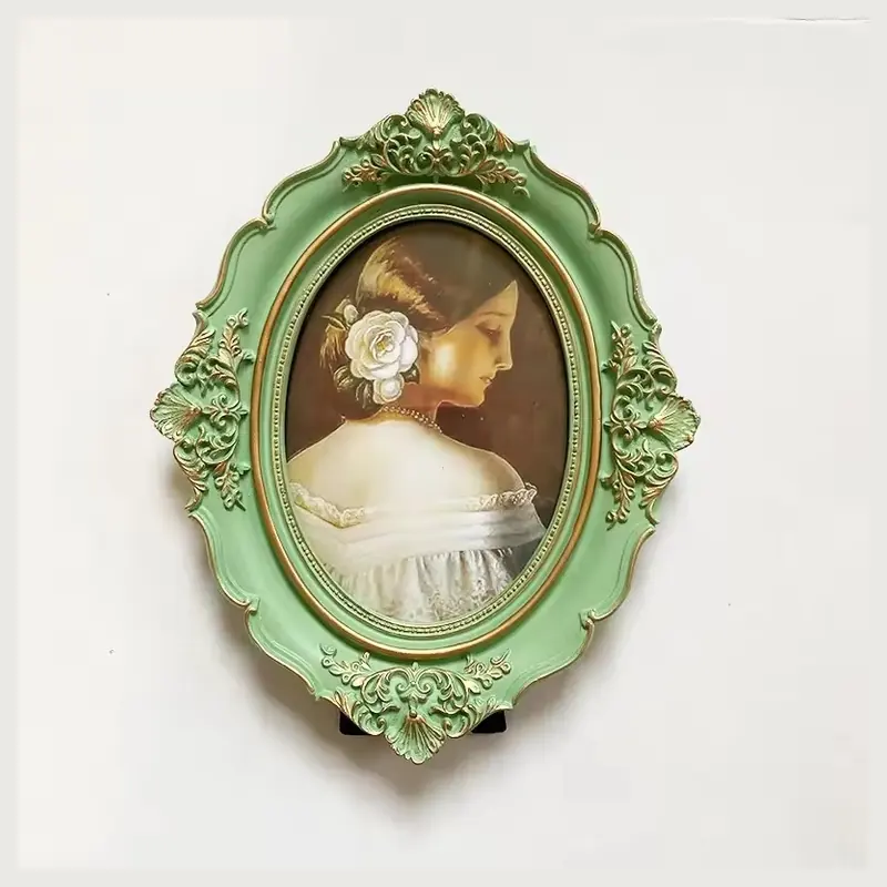 A green oval photo frame with raised floral scrollwork