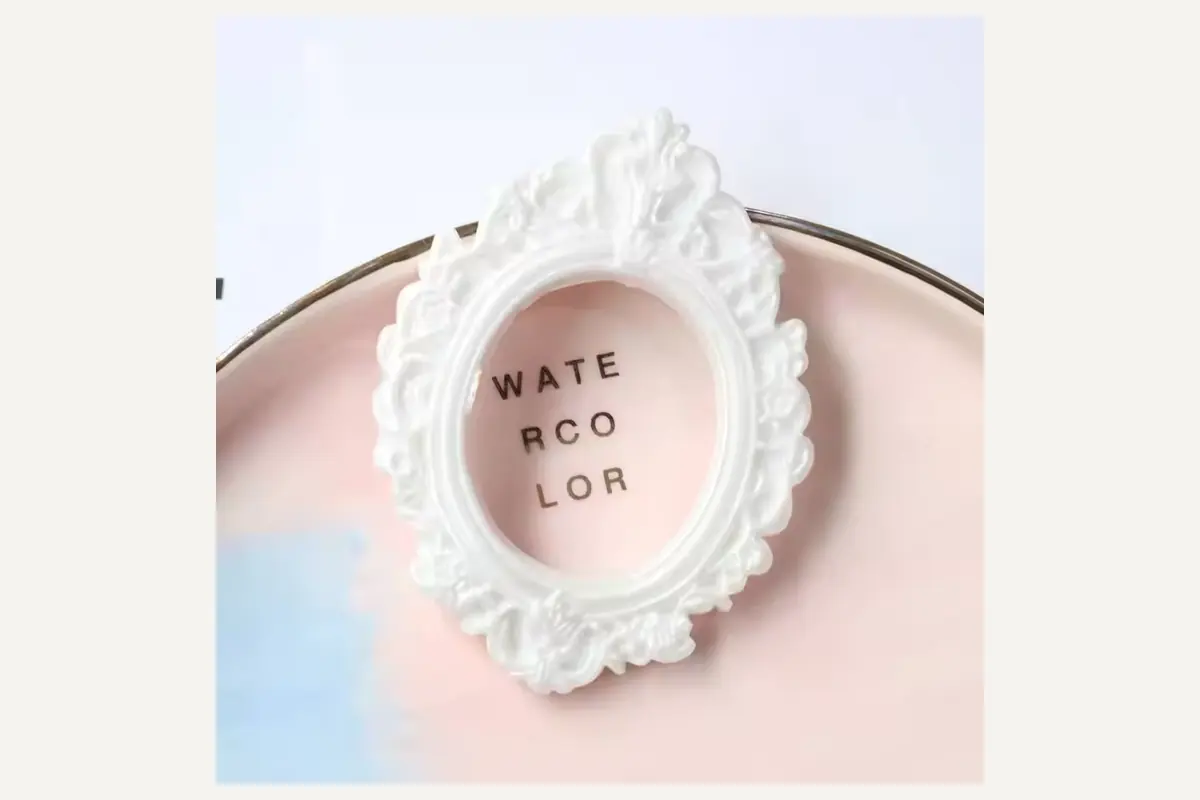 An ivory oval photo frame with raised scrolling decoration