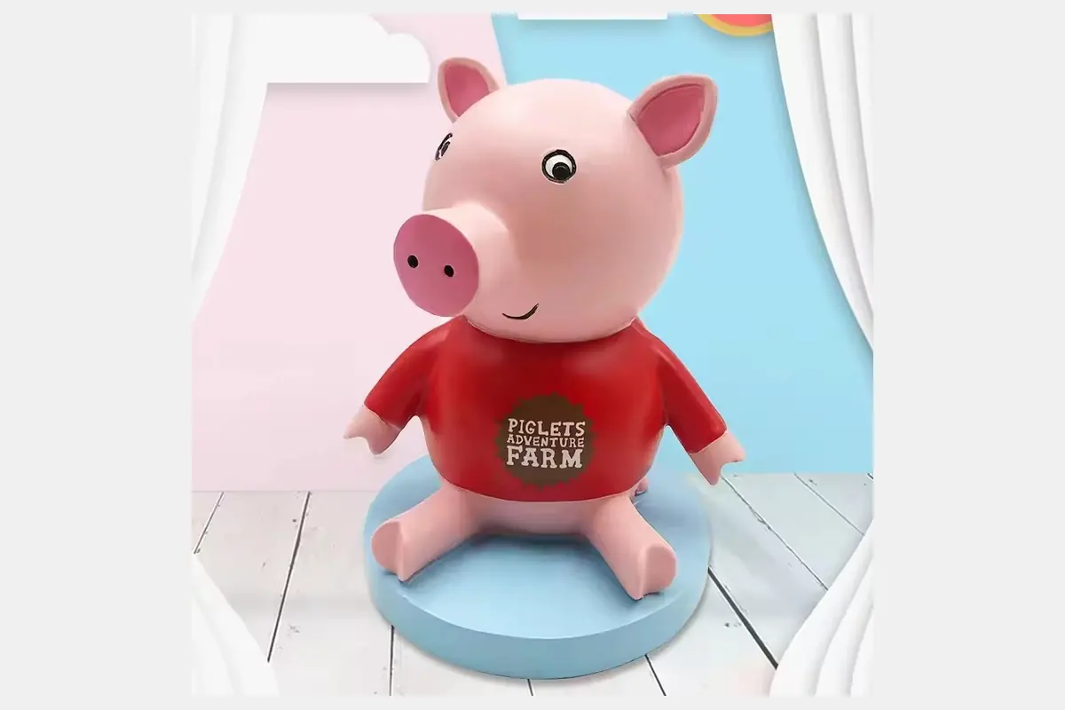 A pink pig coin bank wearing a red shirt with front lettering