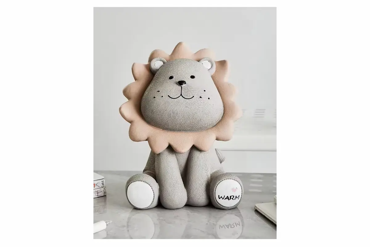 A seated lion-shaped coin bank with a gray face and beige mane