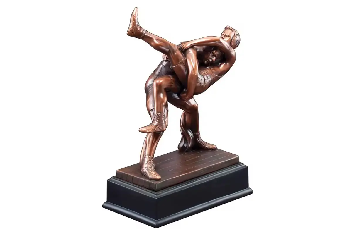 A bronze-colored wrestling sculpture on a stepped rectangular plinth