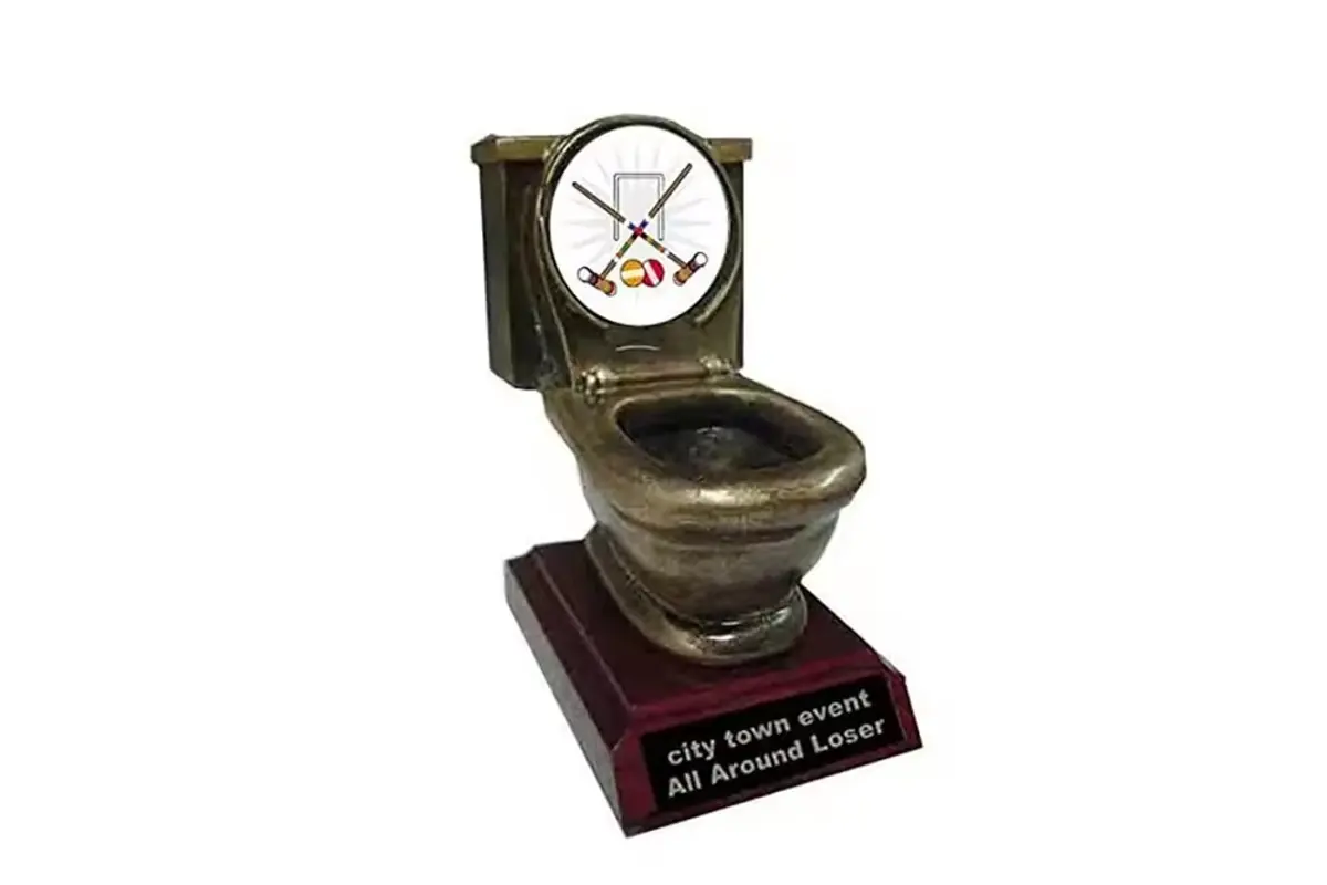A novelty toilet-shaped award on a burgundy display plinth