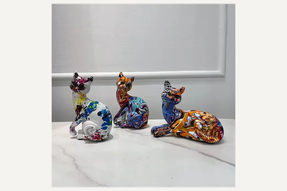 Graffiti-pattern cat figurines on a marble tabletop